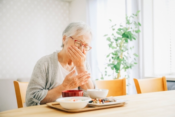 港南台パーク歯科クリニック｜ブログ｜加齢でお口にトラブル？症状と予防法は？｜食事が摂りにくくて悩む女性の画像